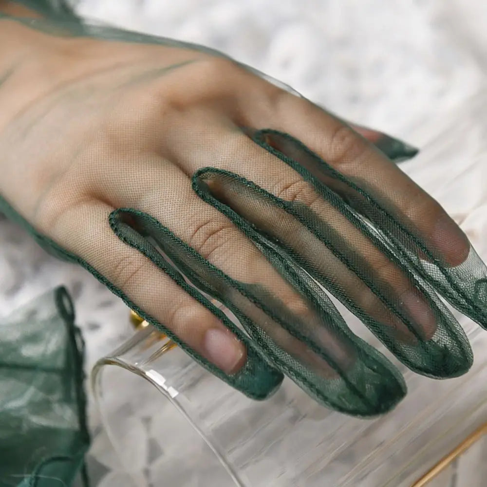 Grande plano dos dedos de uma luva transparente verde-escura sobre uma clutch