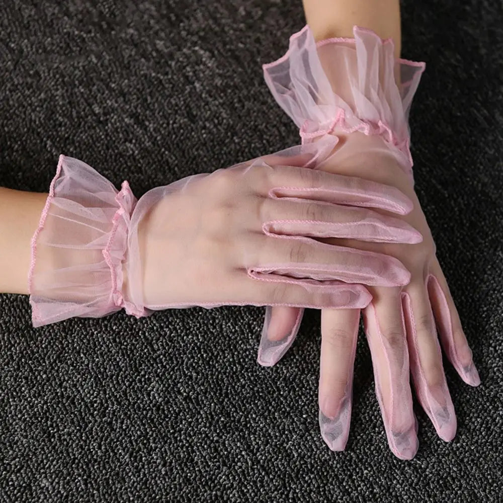 Duas mãos cruzadas com luvas transparentes rosa-pálido com folhos