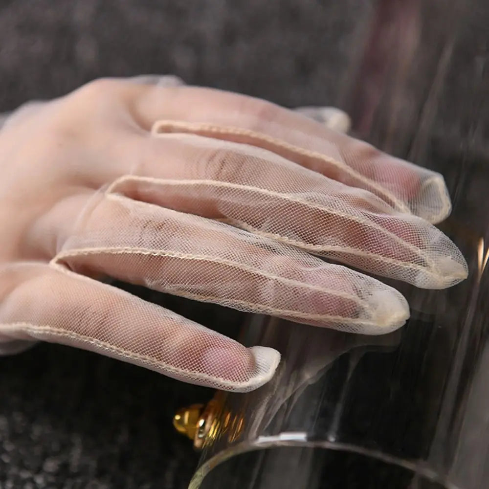 Grande plano dos dedos de uma luva transparente cor de marfim sobre uma clutch