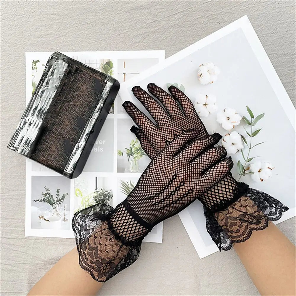 Schwarze Netzhandschuhe mit breiten Spitzenmanschetten neben Baumwollblüten