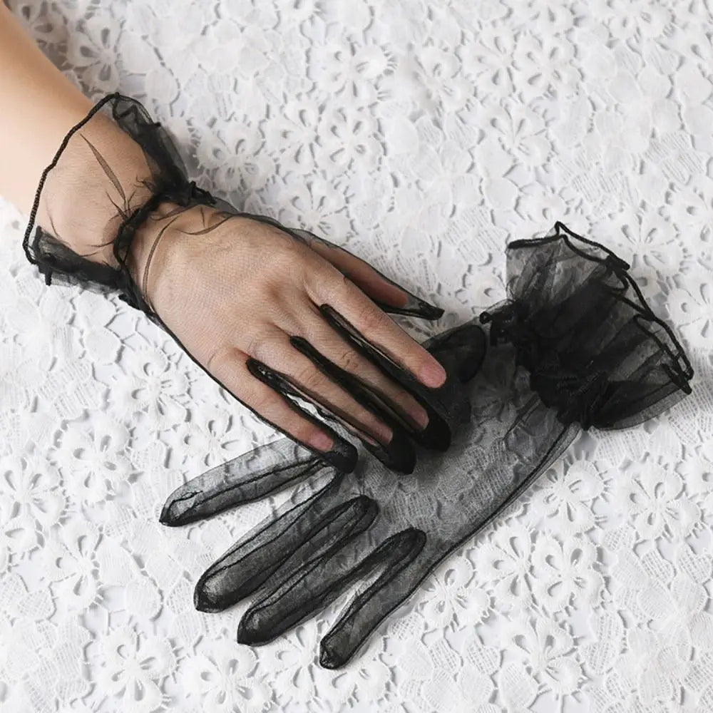 Par de luvas pretas transparentes com folhos sobre renda branca