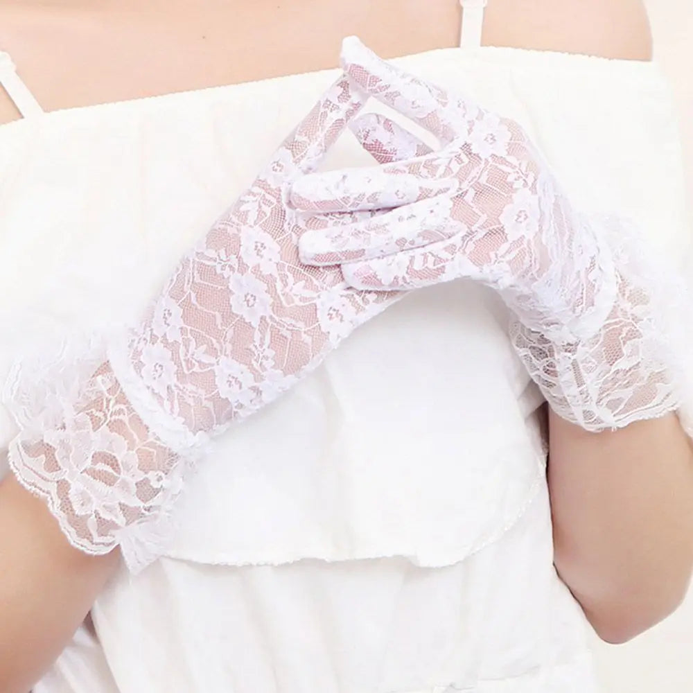 Weiße florale Spitzenhandschuhe mit ausgestellten Manschetten vor einem weißen Oberteil