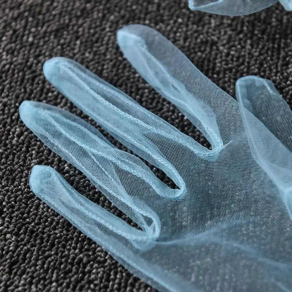 Grande plano dos dedos de uma luva azul-clara de tule transparente