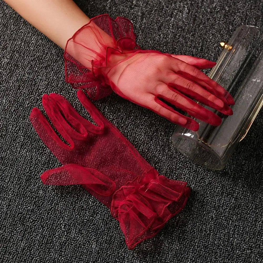 Par de luvas vermelhas de tule com folhos, uma delas usada junto a uma clutch transparente