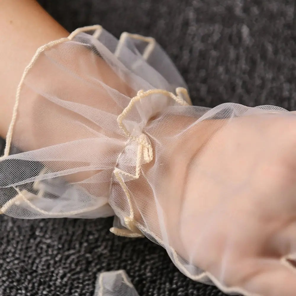 Grande plano do folho de tule cor de marfim de uma luva transparente