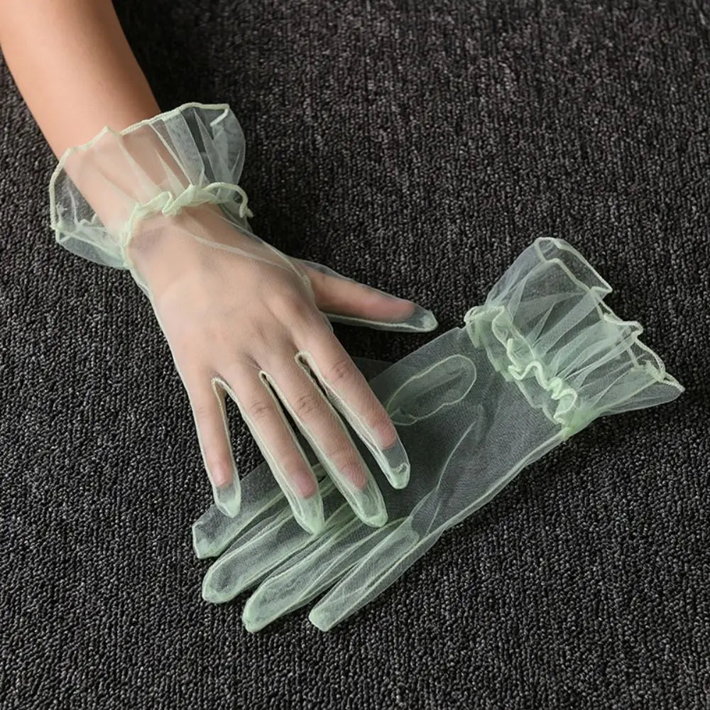 Par de luvas verde-pálido transparentes com folhos, uma delas usada