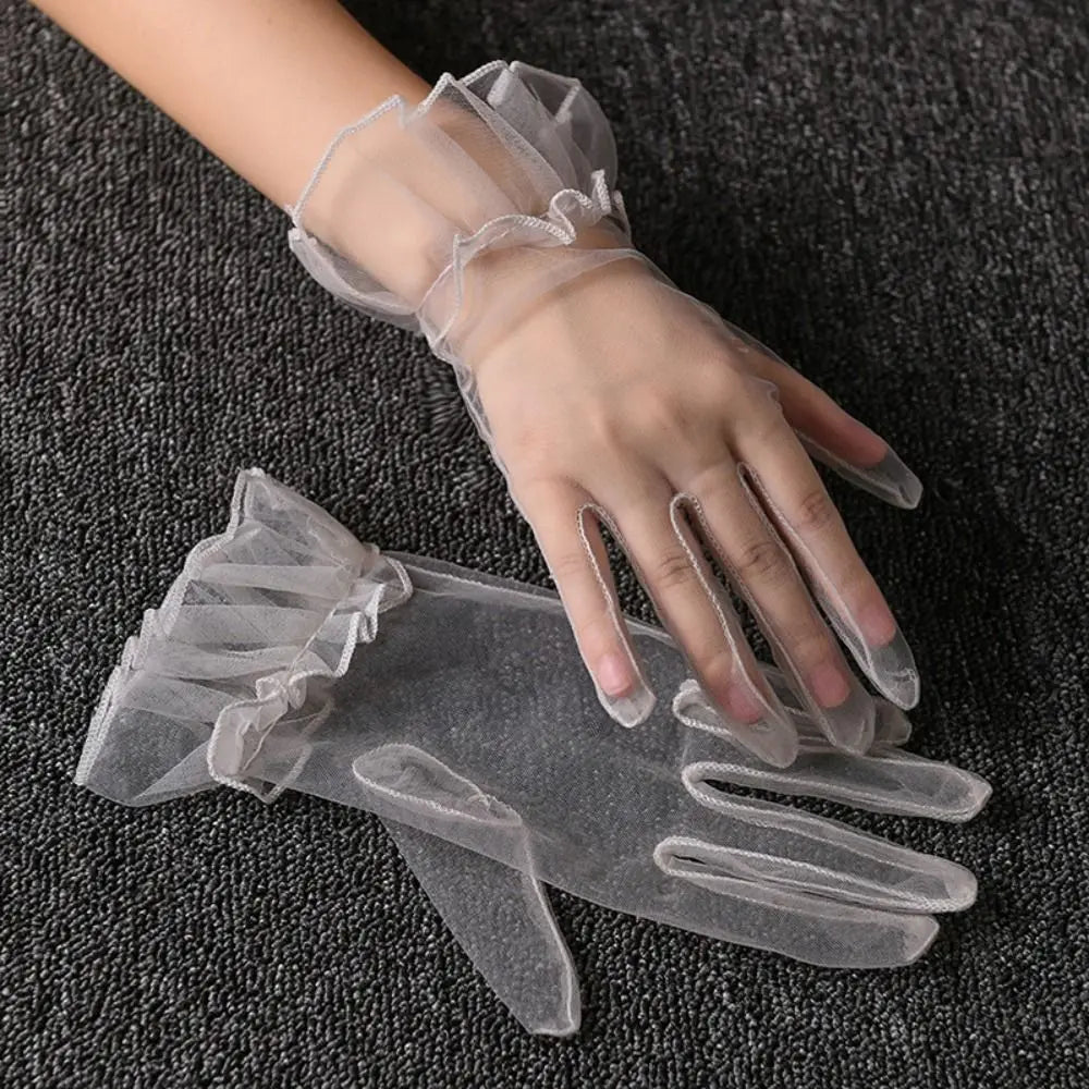 Par de luvas cinzentas-claras transparentes com folhos, uma delas usada