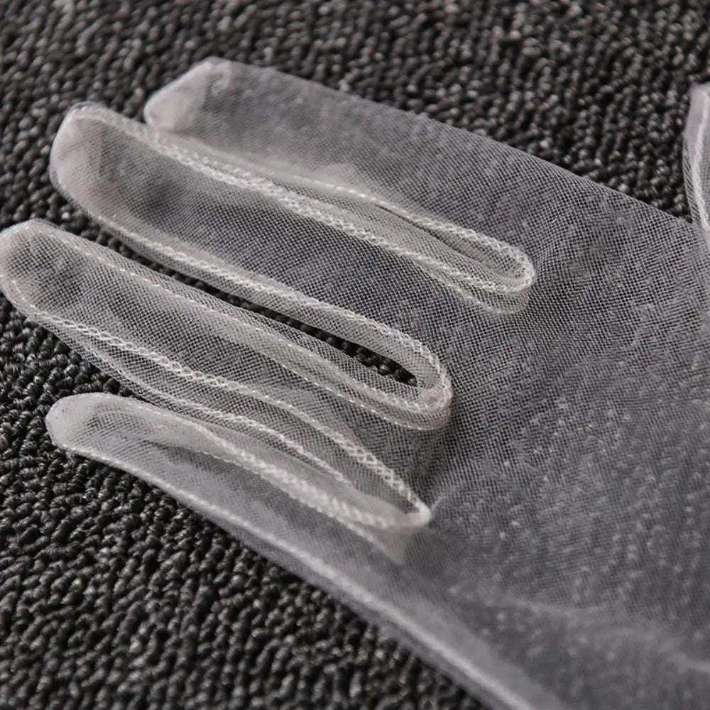 Grande plano de uma luva cinzenta-clara transparente sobre tecido preto texturado