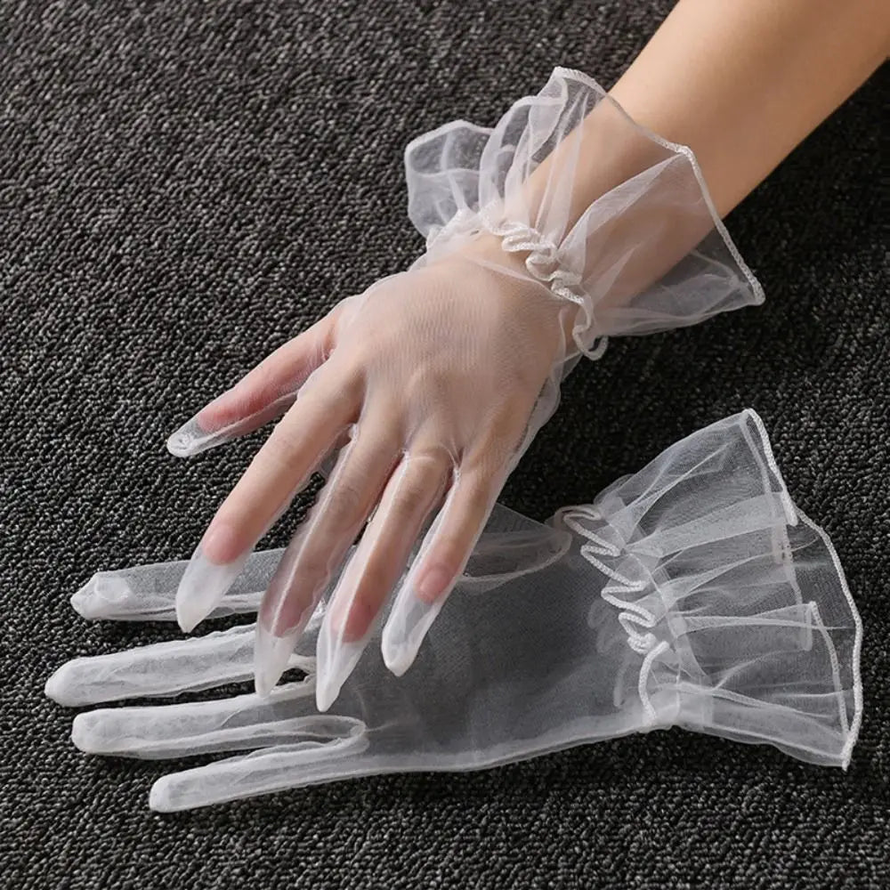 Par de luvas brancas transparentes com folhos largos, uma delas usada